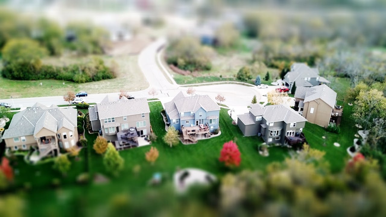 gallery-6 Aerial photo showcasing residential houses in a suburban neighborhood with lush greenery and streets.